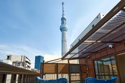 a balcony with two blue chairs in front of a building at HeySky Oshiage in Tokyo