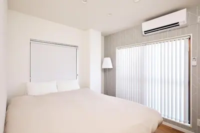 a white bedroom with a large bed and a window at HeySky Oshiage in Tokyo