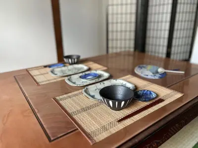 a wooden table with four plates and bowls on it at \u845b\u98fe\u533a\u306e\u4e00\u8ed2\u5bb6\u307e\u308b\u307e\u308b\u8cb8\u3057\u5207\u308a in Tokyo