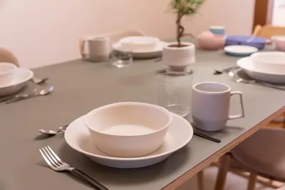a table with a white bowl and plates on it at Homie Hiroo in Tokyo