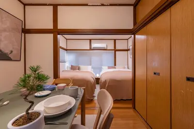 a room with two beds and a table and chairs at Homie Hiroo in Tokyo