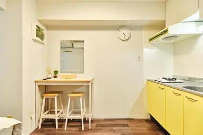 a kitchen with yellow cabinets and a counter with stools at \u65b0\u5bbf\u5340\u6771\u65b0\u5bbf\u7ad9\u8fd1\u9130\u6b4c\u821e\u4f0e\u807d\u4f0a\u52bf\u4e39\u623f\u6e90\u514d\u8cbbWi-Fi#10 in Tokyo