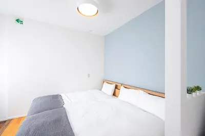 a white bedroom with a bed with a wooden headboard at Japan Tokyo Ueno Ikebukuro private house 5Ppl 3Bed 37m2 for Family in Tokyo