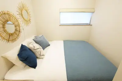 a bedroom with a bed with blue pillows and a mirror at \u897f\u65b0\u5c0f\u5ca94\u4e01\u76ee in Tokyo