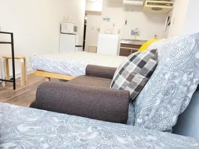 a room with two beds and a couch with a pillow at Shinjuku Tokyo \u6771\u4eac\u65b0\u5bbf SS in Wada