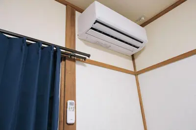 a white air conditioner on the ceiling of a room at 15minutes walk from Skytree -Mukojima House- in Tokyo