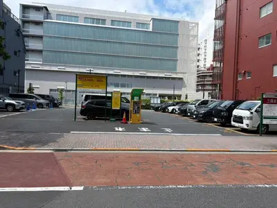 a parking lot with cars parked in front of a building at Tokyo Oji Apartment 3B in Tokyo