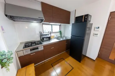 a kitchen with a black refrigerator and wooden cabinets at Kameari House Serene Japanese-Inspired Stay in Residential Tokyo in Tokyo