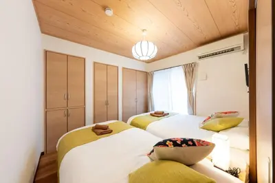 two beds in a room with wooden ceilings at Kameari House Serene Japanese-Inspired Stay in Residential Tokyo in Tokyo