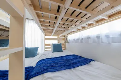 a bed in a small room with blue pillows at 12min walk from Ikebukuro Station Max 15 people in Tokyo