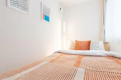 a bedroom with a bed with an orange pillow on it at Direct to Asakusa Ginza & NRT HND 2025 New House in Tokyo