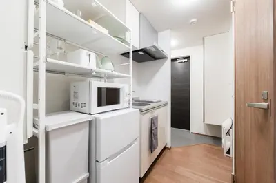 a kitchen with white cabinets and a microwave at THE CAMINO Nakano 302 in Tokyo