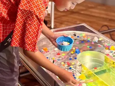 a young boy playing with beads in a play table at OMATSURI BASE Nakanoshimbashi in Tokyo
