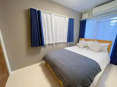 a bedroom with a large bed with blue curtains at \u65b0\u5bbf\u5fa1\u82d1 \u5f92\u6b698\u5206 \u65b0\u5bbf\u4e09\u4e01\u76ee\u99c5\u5f92\u6b698\u5206 WiFi\u7121\u6599 in Tokyo