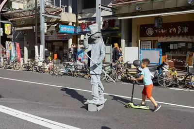 a young boy riding a scooter with a statue in the street at \u677e\u5c4b\u30db\u30c6\u30eb4\u968e in Tokyo