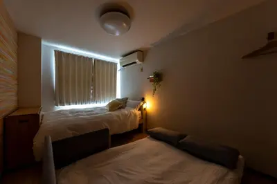 a small room with two beds and a window at Minamishinagawa A-yokocho Base in Tokyo