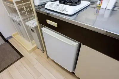 a kitchen with a refrigerator and a white dishwasher at Minamishinagawa A-yokocho Base in Tokyo