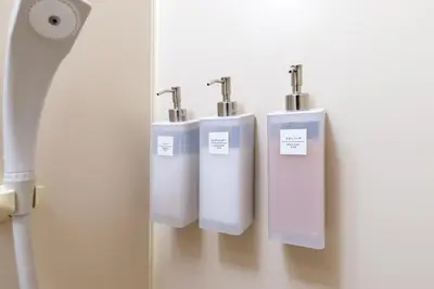 three white urinals on a wall in a bathroom at Minamishinagawa A-yokocho Base in Tokyo