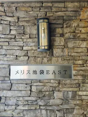 a street sign and a light on a brick wall at \u30e1\u30ea\u30b9\u6c60\u888bEast 402 in Tokyo