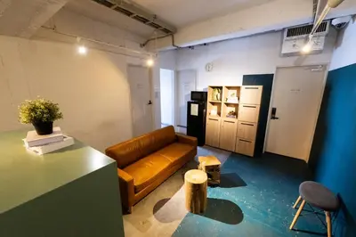 a living room with a leather couch and a table at Imano Tokyo Hostel in Tokyo