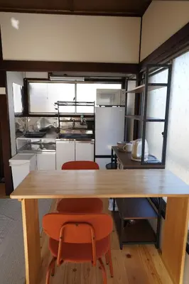 a kitchen with a wooden table and two orange chairs at tonema in Tokyo