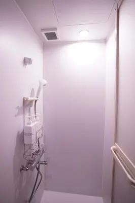 a white bathroom with a hair dryer on the wall at tonema in Tokyo