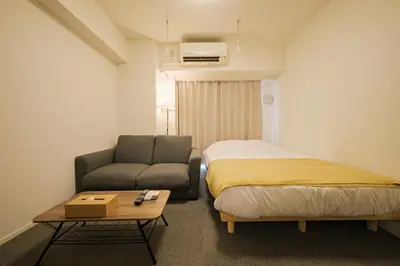 a room with a bed and a couch and a table at \u30a2\u30ec\u30b9\u30b0\u30fc\u30c6\u65e9\u7a32\u7530 in Tokyo