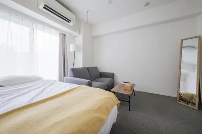 a bedroom with a bed and a chair and a mirror at \u30a2\u30ec\u30b9\u30b0\u30fc\u30c6\u65e9\u7a32\u7530 in Tokyo