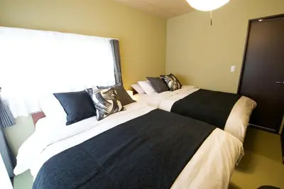 two beds in a bedroom with a window at Realization INN Horikiri in Tokyo