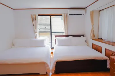 two beds in a small room with a window at Akira Hiro House in Tokyo