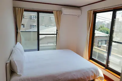 a bedroom with a white bed and a large window at Akira Hiro House in Tokyo
