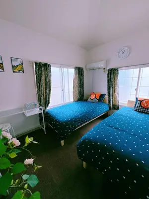 two beds in a room with blue comforters and windows at M-house in Tokyo