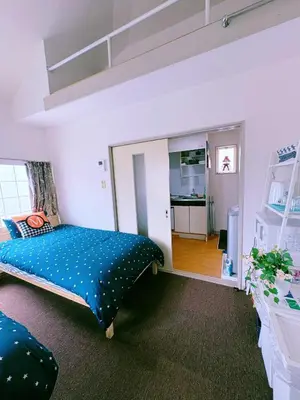 a bedroom with a bed with a blue comforter at M-house in Tokyo