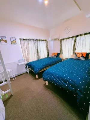 a bedroom with two beds and two windows at M-house in Tokyo