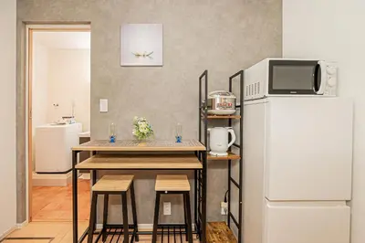 a kitchen with a table with stools and a refrigerator at 101 6-min walk from Higashi-Jūjō Station Cozy 1-Bedroom Apartment Direct Access to Akihabara & Ueno in Tokyo