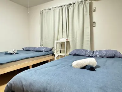 a bedroom with two beds with blue sheets and a window at TD House 3-min Walk Easy Access Shinjuku, Shibuya, Asakusa, Ueno in Tokyo