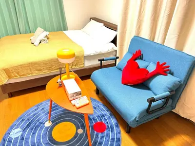 a bedroom with a blue chair with a red chicken pillow at TD House 3-min Walk Easy Access Shinjuku, Shibuya, Asakusa, Ueno in Tokyo