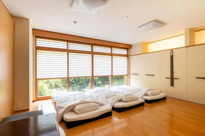 a bedroom with two beds in front of a large window at SHINJUKU Garden-house in Tokyo