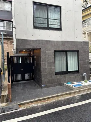 a building with a black gate on a street at 31 \u3068\u308a\u3063\u3071\u30fc\u305a\u30db\u30c6\u30eb\u9ad8\u7530\u99ac\u5834 in Tokyo