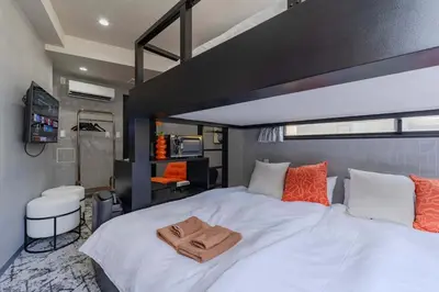 a bedroom with a large white bed with orange pillows at KOKOON Hotel Shibuya 301 in Tokyo