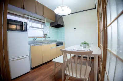 a kitchen with a small table and a white refrigerator at Voyager Inn in Tokyo