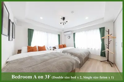 two beds in a bedroom with green curtains at Bell tree Higashi-Mukojima in Tokyo