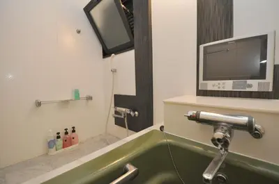 a bathroom with a tub with a tv on the wall at Hotel Boston Club (Adult Only) in Tokyo