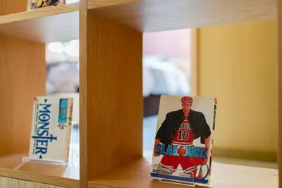 a book on a shelf with a picture of a man at Tokyo Manga Stay \u99c51\u5206\u8cb8\u5207\u306785\u5e73\u7c73 \u65e5\u672c\u306e\u6709\u540d\u30de\u30f3\u30ac\u304c\u8aad\u3081\u308b\u5bbf 9\u540d\u307e\u3067OK in Tokyo