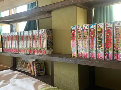 a bunch of books sitting on a shelf at Tokyo Manga Stay \u99c51\u5206\u8cb8\u5207\u306785\u5e73\u7c73 \u65e5\u672c\u306e\u6709\u540d\u30de\u30f3\u30ac\u304c\u8aad\u3081\u308b\u5bbf 9\u540d\u307e\u3067OK in Tokyo