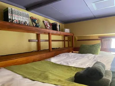 a bedroom with a bed and a shelf with books at Tokyo Manga Stay \u99c51\u5206\u8cb8\u5207\u306785\u5e73\u7c73 \u65e5\u672c\u306e\u6709\u540d\u30de\u30f3\u30ac\u304c\u8aad\u3081\u308b\u5bbf 9\u540d\u307e\u3067OK in Tokyo