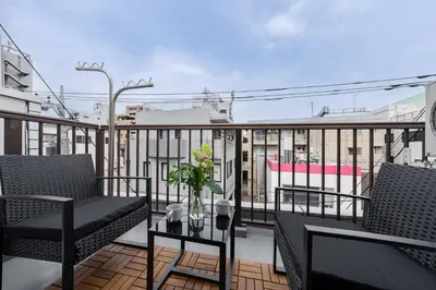 a balcony with two chairs and a table with flowers on it at Tokyo Manga Stay \u99c51\u5206\u8cb8\u5207\u306785\u5e73\u7c73 \u65e5\u672c\u306e\u6709\u540d\u30de\u30f3\u30ac\u304c\u8aad\u3081\u308b\u5bbf 9\u540d\u307e\u3067OK in Tokyo