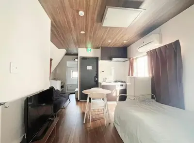 a bedroom with a bed and a table and a kitchen at \u677e\u5c4b\u30db\u30c6\u30eb5\u968e in Tokyo
