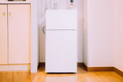 a white refrigerator in a kitchen next to a door at Showa Bloom Near Shinjuku Station in Tokyo