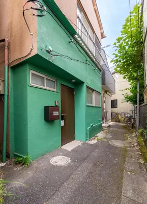 a green building with a door on the side of it at Shinkoiwa HOUSE in Tokyo